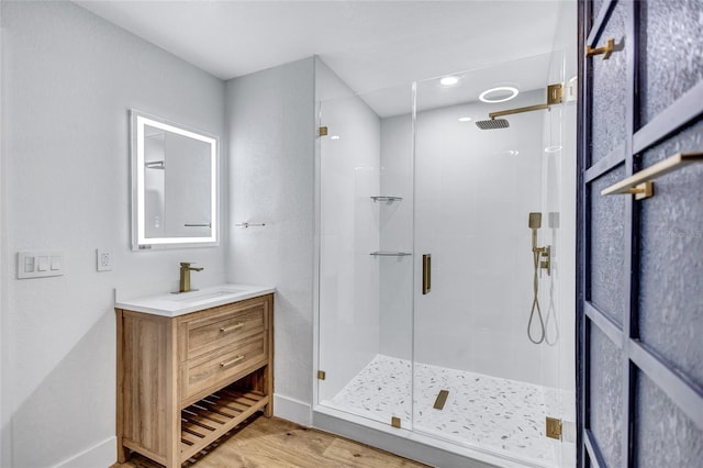 bathroom with hardwood / wood-style flooring, vanity, and walk in shower