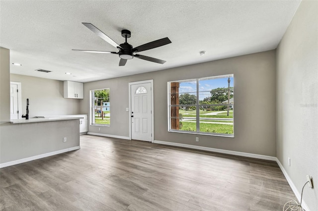 102 Shore Dr E, Oldsmar, FL 34677 - unfurnished living room featuring ceiling fan, wood finished floors, and a textured ceiling