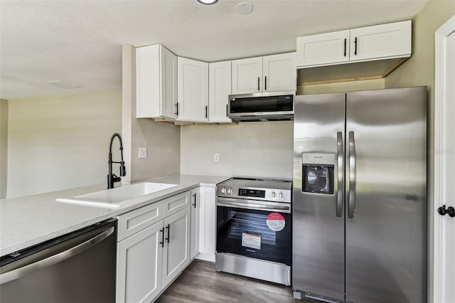 102 Shore Dr E, Oldsmar, FL 34677 - kitchen featuring stainless steel appliances, white cabinets, dark wood-type flooring, a textured ceiling, and light stone countertops