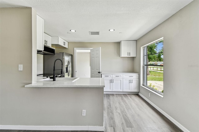 102 Shore Dr E, Oldsmar, FL 34677 - kitchen featuring white cabinetry, light wood-style flooring, light countertops, recessed lighting, and a peninsula