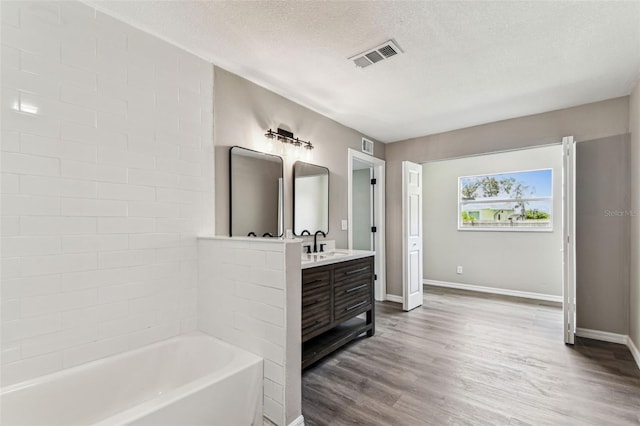 102 Shore Dr E, Oldsmar, FL 34677 - bathroom featuring a bath, vanity, a textured ceiling, and wood finished floors