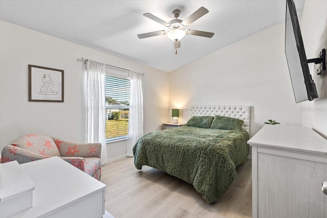 bedroom with ceiling fan, a textured ceiling, and light hardwood / wood-style flooring