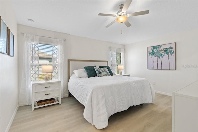 bedroom with ceiling fan, light hardwood / wood-style floors, and multiple windows