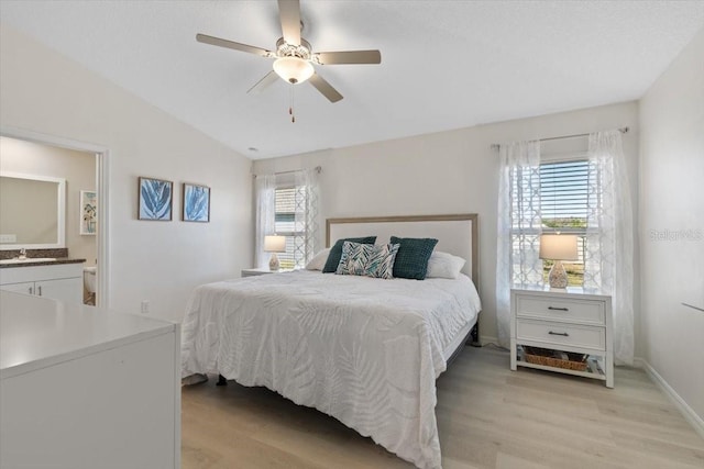 bedroom featuring light hardwood / wood-style floors, vaulted ceiling, multiple windows, and ceiling fan