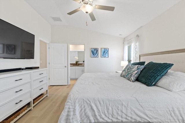 bedroom with ceiling fan, lofted ceiling, ensuite bathroom, and light hardwood / wood-style flooring