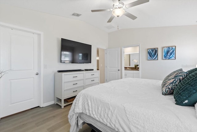 bedroom featuring ensuite bath, ceiling fan, lofted ceiling, and light wood-type flooring