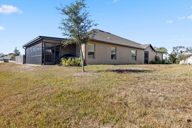 rear view of property with a lawn and a sunroom