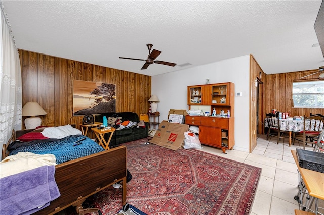 tiled bedroom with wood walls, ceiling fan, and a textured ceiling