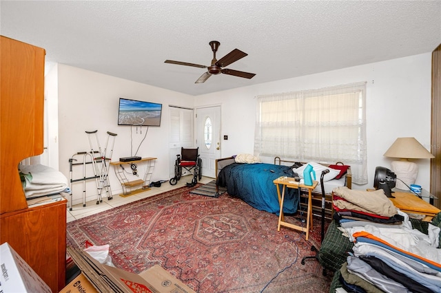 bedroom with tile patterned flooring, a textured ceiling, and ceiling fan