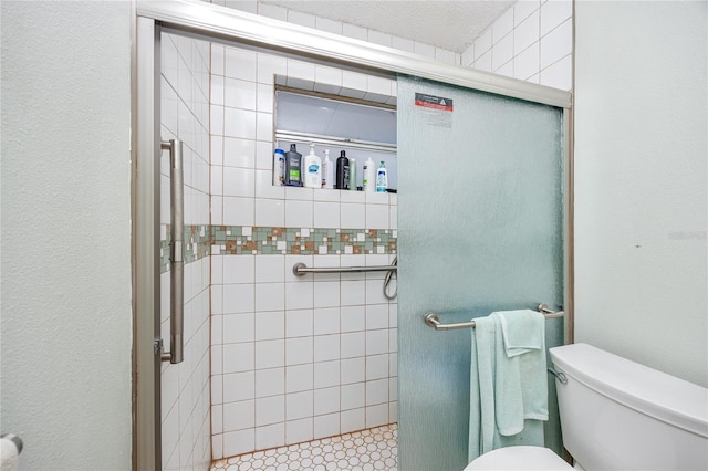 bathroom featuring a textured ceiling, toilet, and walk in shower