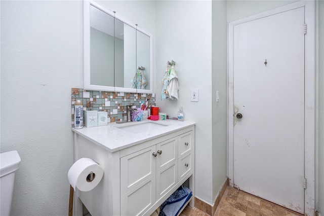 bathroom with vanity, toilet, and backsplash