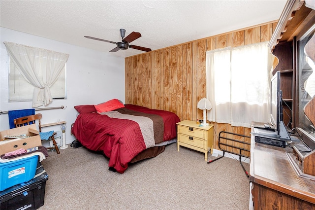 carpeted bedroom featuring a textured ceiling, ceiling fan, and wood walls