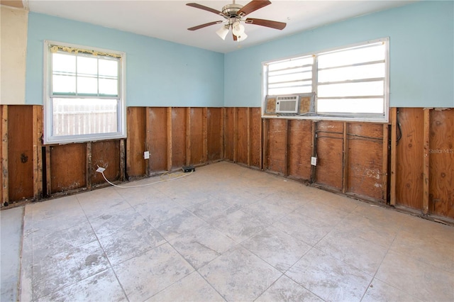 empty room with ceiling fan and wood walls