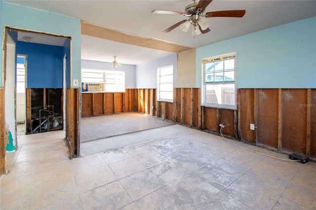 empty room featuring wood walls, ceiling fan, and cooling unit