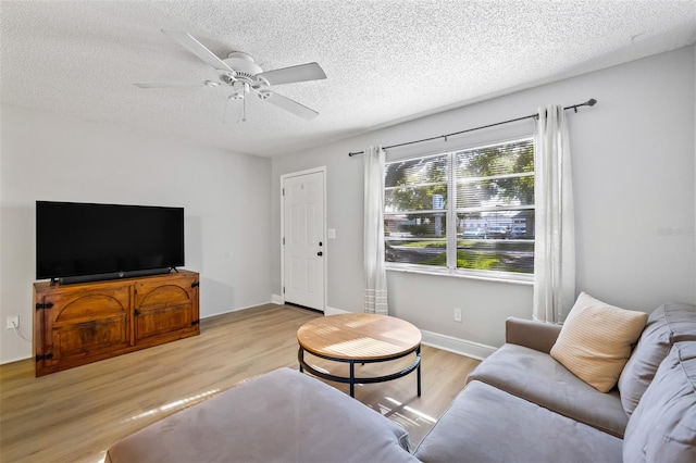 living room featuring a textured ceiling, light wood-type flooring, and ceiling fan