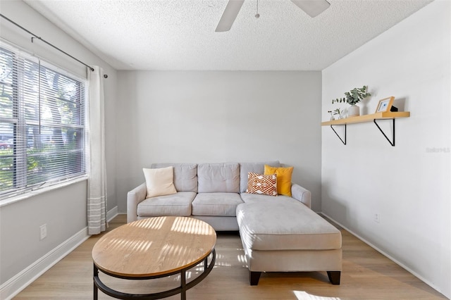 living area with ceiling fan, light hardwood / wood-style floors, and a textured ceiling