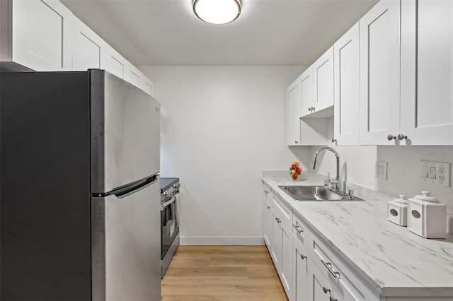 kitchen with sink, white cabinets, light hardwood / wood-style flooring, and appliances with stainless steel finishes