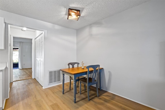 dining room featuring light hardwood / wood-style flooring and a textured ceiling