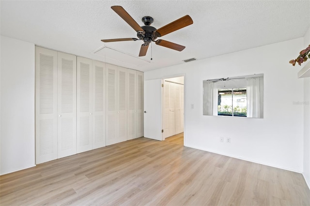 unfurnished bedroom featuring ceiling fan, a textured ceiling, and light wood-type flooring