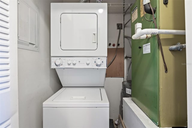 clothes washing area with stacked washer and dryer and heating unit