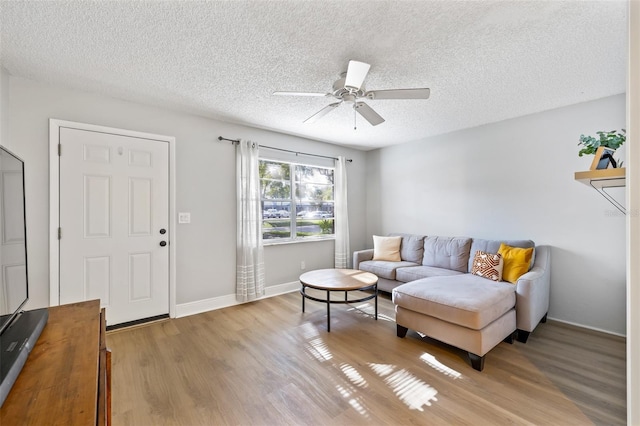 living room with ceiling fan, light hardwood / wood-style floors, and a textured ceiling