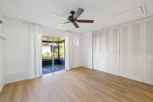 unfurnished bedroom with access to outside, ceiling fan, light hardwood / wood-style floors, and a textured ceiling