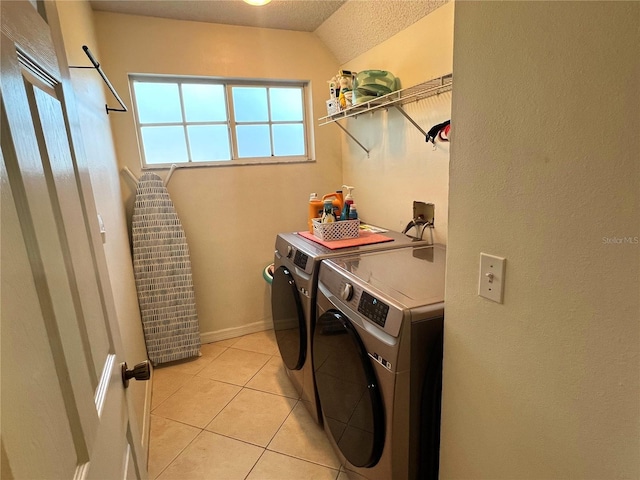 washroom featuring washer and clothes dryer, light tile patterned floors, and a textured ceiling