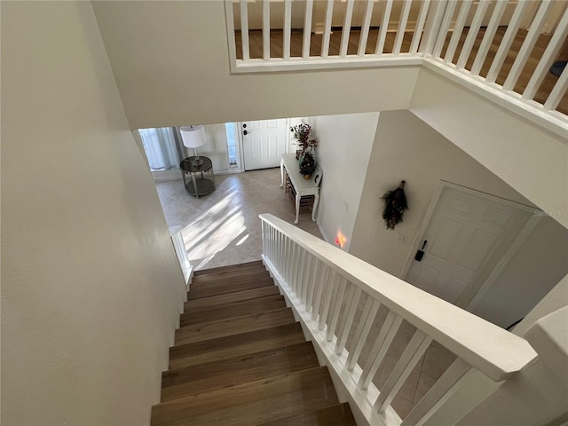 staircase with a towering ceiling and wood-type flooring