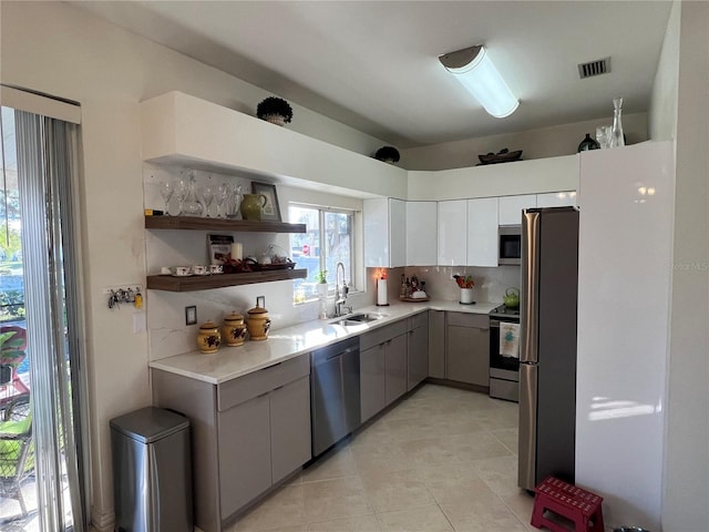 kitchen with backsplash, gray cabinetry, stainless steel appliances, sink, and white cabinets