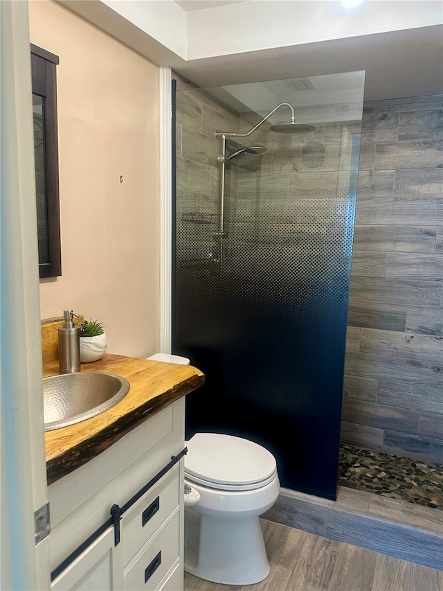 full bath with a walk in shower, toilet, wood finished floors, and vanity