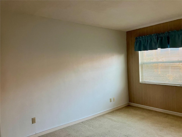 spare room featuring light colored carpet and baseboards