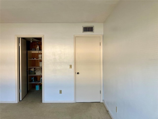 unfurnished bedroom with light carpet, baseboards, a spacious closet, and visible vents