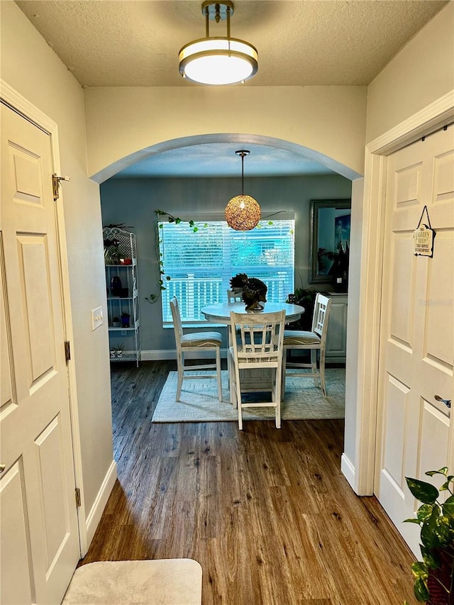 dining space featuring dark wood-type flooring and a textured ceiling