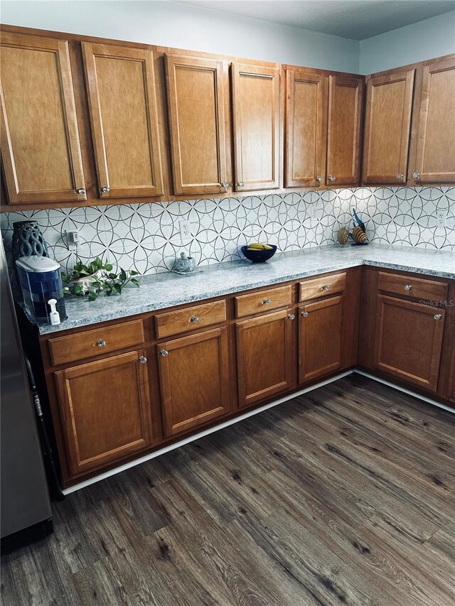 kitchen with light stone countertops, backsplash, and dark hardwood / wood-style flooring