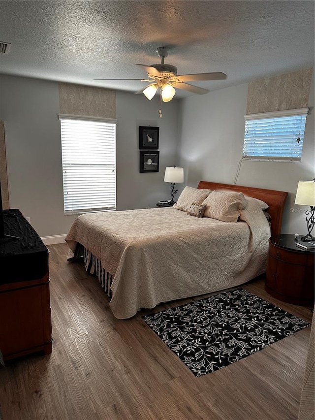 bedroom featuring ceiling fan, multiple windows, hardwood / wood-style floors, and a textured ceiling