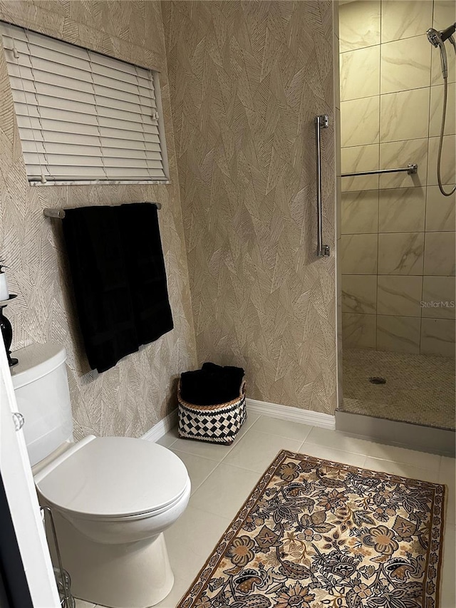 bathroom with toilet, tile patterned floors, and tiled shower