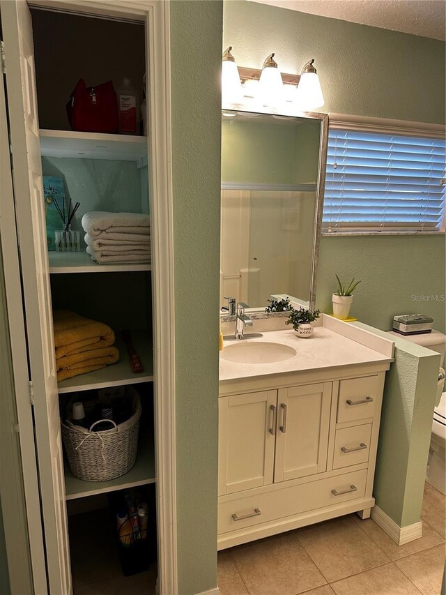 bathroom with toilet, vanity, and tile patterned flooring