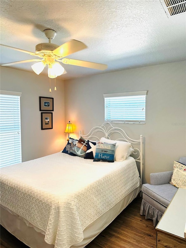 bedroom with ceiling fan, dark wood-type flooring, and a textured ceiling