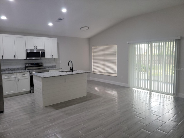 kitchen featuring white cabinets, black electric range oven, an island with sink, and vaulted ceiling