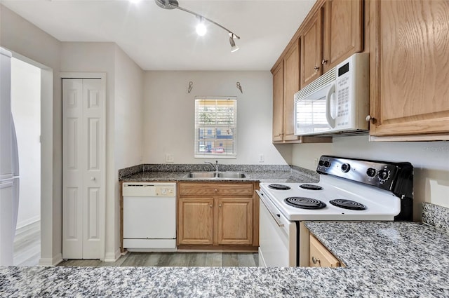 kitchen with light wood-type flooring, white appliances, sink, and dark stone counters