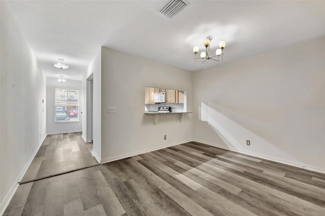 unfurnished room with dark wood-type flooring, a textured ceiling, and an inviting chandelier