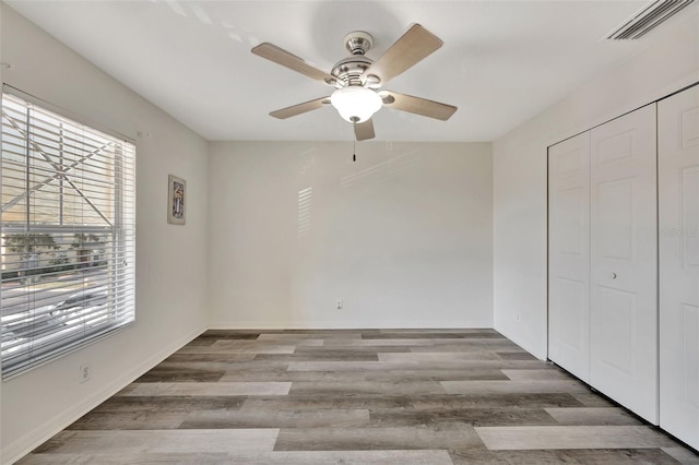 unfurnished bedroom with a closet, light hardwood / wood-style floors, multiple windows, and ceiling fan