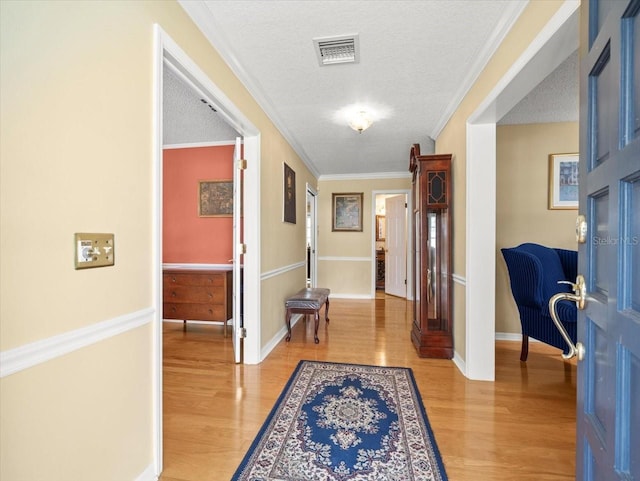 hall featuring hardwood / wood-style flooring, crown molding, and a textured ceiling