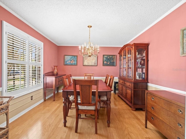 dining room with a notable chandelier, light hardwood / wood-style floors, ornamental molding, and a textured ceiling