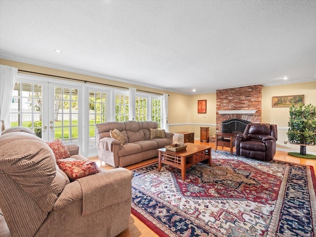 living room featuring french doors, light hardwood / wood-style floors, a brick fireplace, and crown molding