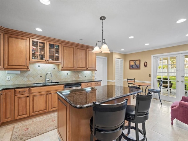 kitchen featuring sink, hanging light fixtures, stainless steel dishwasher, dark stone counters, and a kitchen island