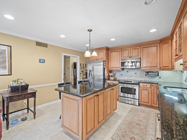 kitchen featuring pendant lighting, backsplash, sink, dark stone countertops, and stainless steel appliances