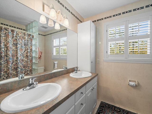 bathroom with toilet, a wealth of natural light, and tile walls