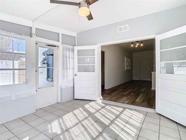 tiled spare room featuring visible vents and ceiling fan