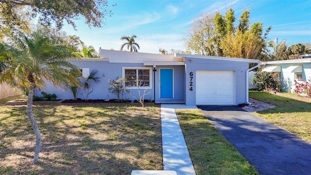 mid-century inspired home with a garage, driveway, a front lawn, and stucco siding